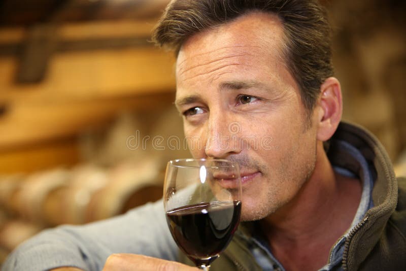 Winemaker smelling red wine in cellar