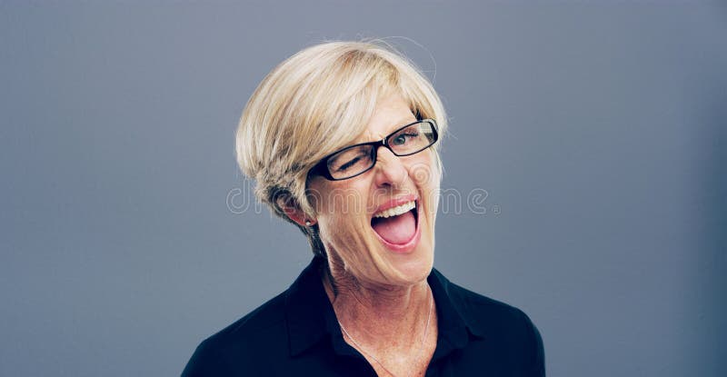 Wink feliz y retrato de una mujer madura en el estudio por un logro bien hecho y buena suerte. Sonreír espacio y persona foto de archivo