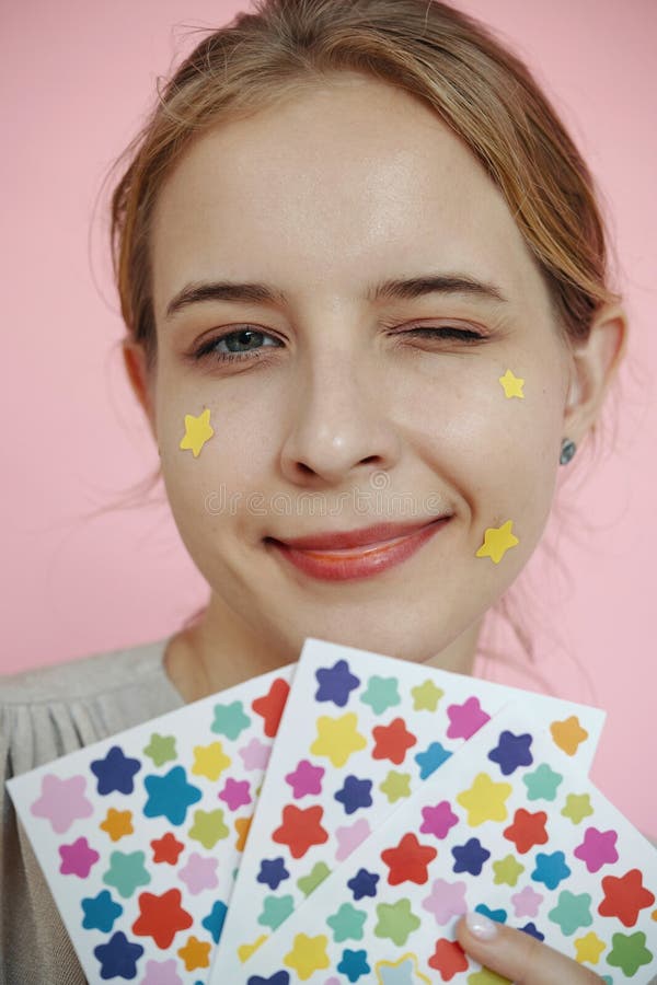 Winking Woman Holding Star-Shaped Stickers on Pink Background stock images