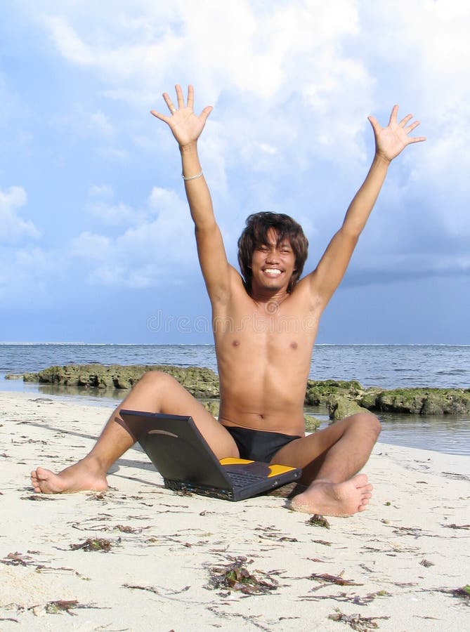 Asian boy on tropical beach with laptop, cheering with arms high: concept of winner. Asian boy on tropical beach with laptop, cheering with arms high: concept of winner.