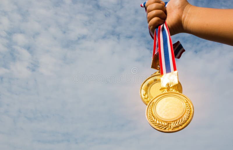 Winnaarhand opgeheven en holding twee gouden medailles met Thais lint royalty-vrije stock afbeelding Winnaarhand opgeheven en holding twee gouden medailles met Thais lint royalty-vrije stock afbeelding