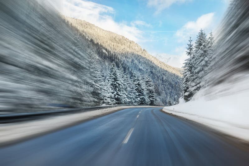 Winter alpine road curve landscape with forest, mountains and blue sky on background at bright cold sunny day. Car trip family