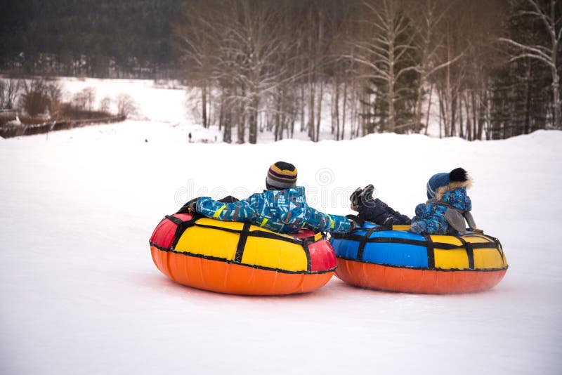 children are rolling down snow tubing