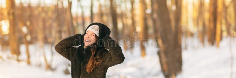 Winter cold weather woman protecting ears holding warm hat over earmuffs forest background banner panorama. Frostbite