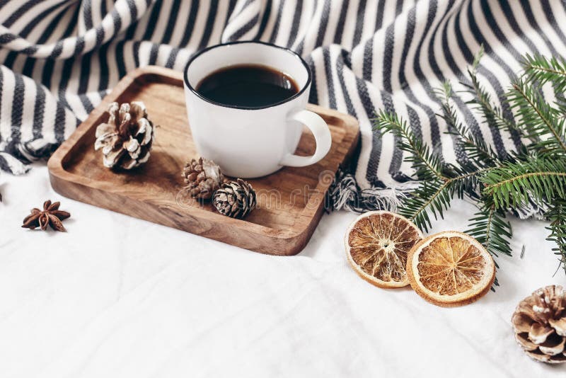 Winter composition. Breakfast in bed. Cup of coffee on wooden tray, wool blanket, fir tree branch, orange slices and