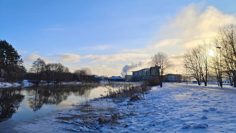 In winter everything is covered with snow, and the river in the city park is partially covered with ice. There is a footpath along stock photography