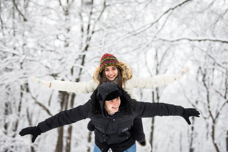 Winter fun couple playful together during winter holidays vacation outside in snow forest.