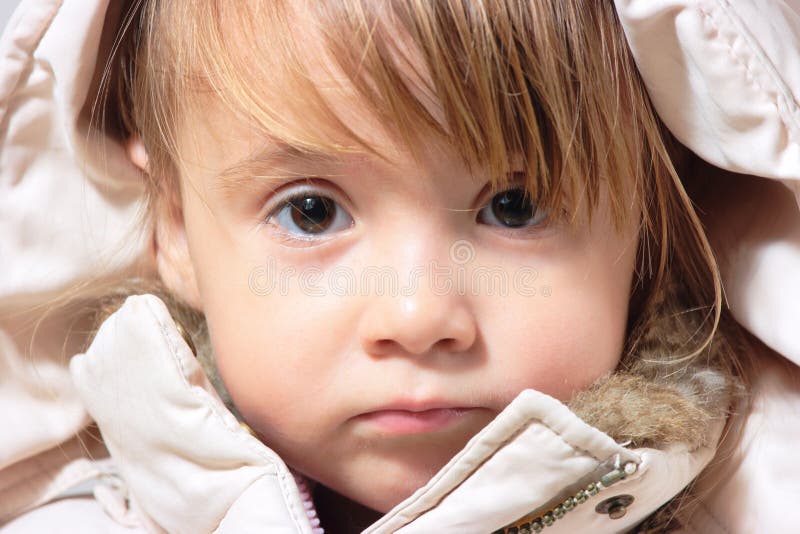 Close-up of lovely winter-dressed baby girl looking directly in camera. Close-up of lovely winter-dressed baby girl looking directly in camera