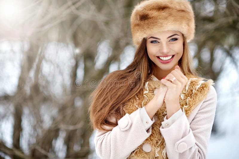 Winter girl portrait. Beautiful smiling woman in snowy park