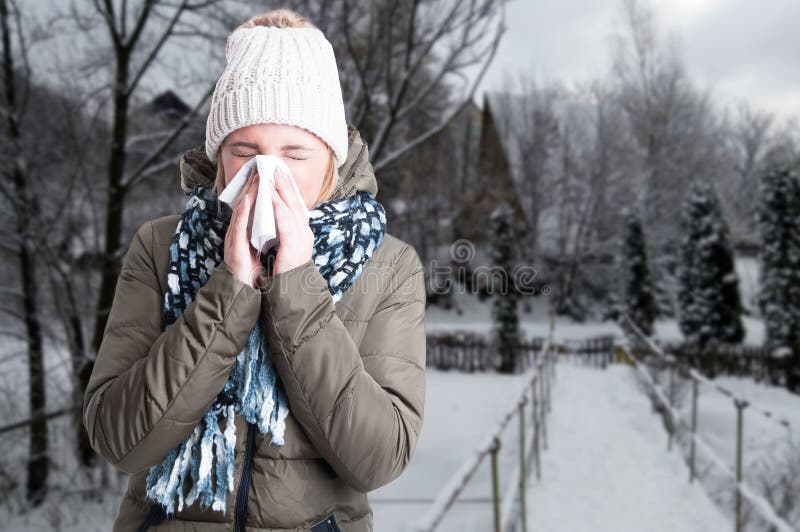 Winter illness concept with woman blowing into napkin