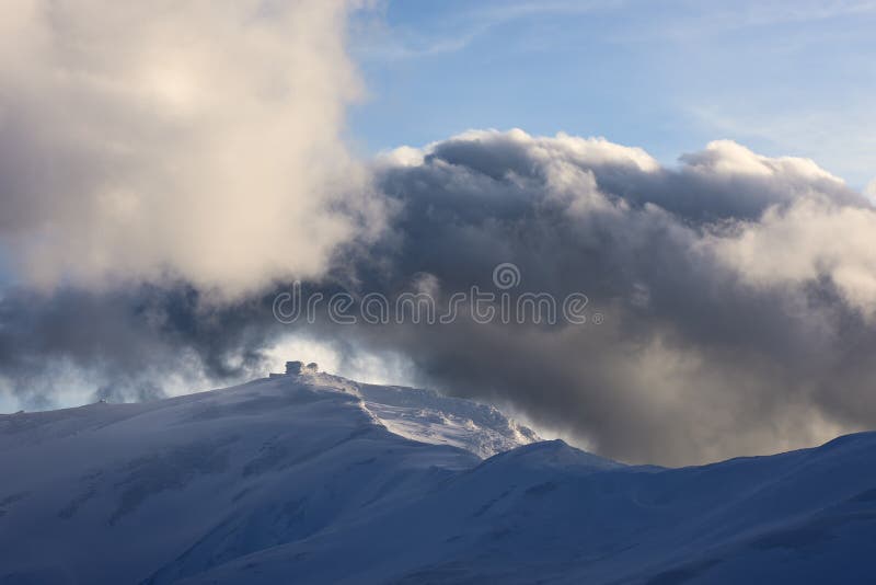 Winter landscape with the old observatory on the top of the mountain. Sky with beautiful clouds in the evening sunlight. Carpathians, Ukraine, Europe. Winter landscape with the old observatory on the top of the mountain. Sky with beautiful clouds in the evening sunlight. Carpathians, Ukraine, Europe