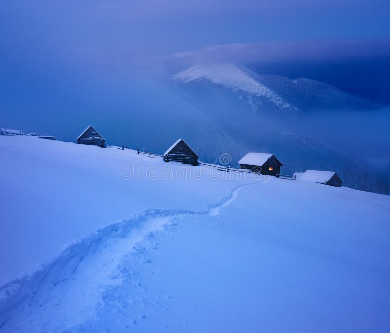 Winter landscape with mountain huts and a path in the snow