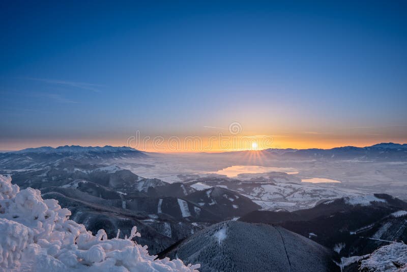 Zimná krajina pri východe slnka z vrchu veľký choc v zime s hmlou v doline, pohľad na nízke a vysoké tatry a liptovskú maru