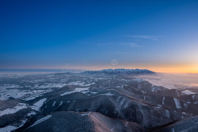 Zimná krajina pri východe slnka z vrchu veľký choc v zime s hmlou v doline, pohľad na nízke a vysoké tatry a liptovskú maru