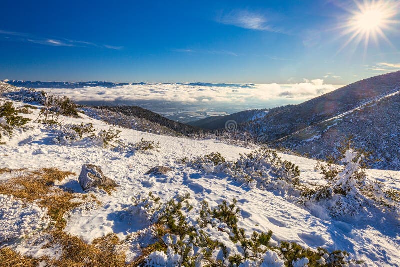 Zimní horská krajina za slunečného dne s mlhou v údolích