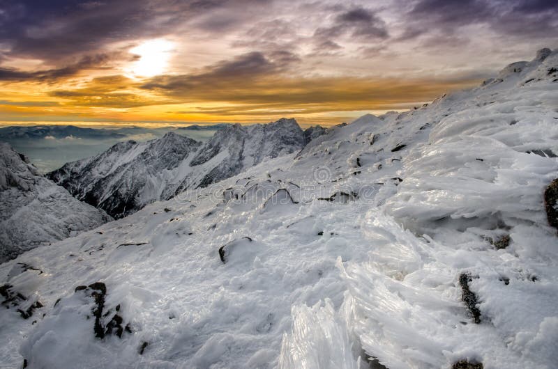 Zimní hory se zmrzlým sněhem a námrazou při západu slunce