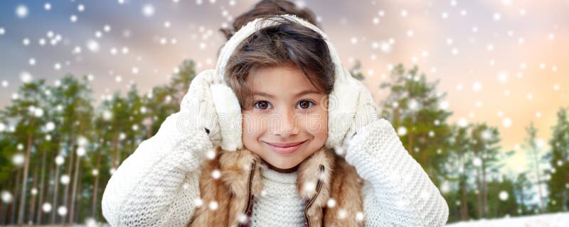 Little girl wearing earmuffs over winter forest