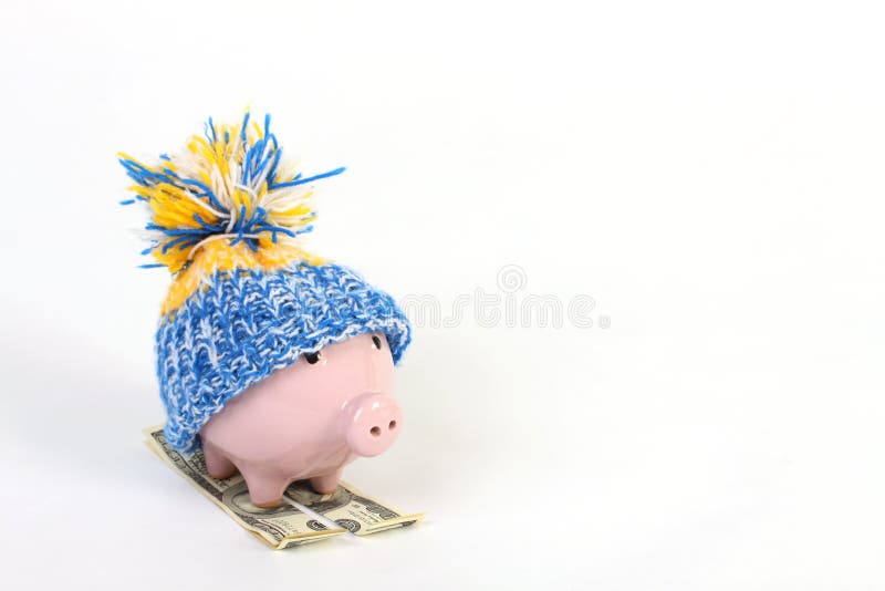 Winter piggy bank with hat with pom-pom standing on skies of greenback hunderd dollars