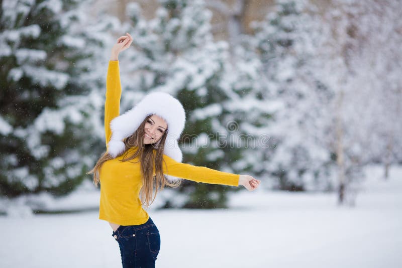 Winter portrait of beautiful smiling woman with snowflakes in white furs