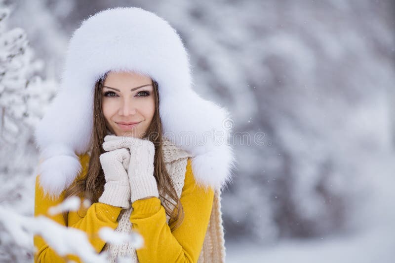 Winter portrait of beautiful smiling woman with snowflakes in white furs