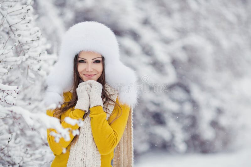 Winter portrait of beautiful smiling woman with snowflakes in white furs