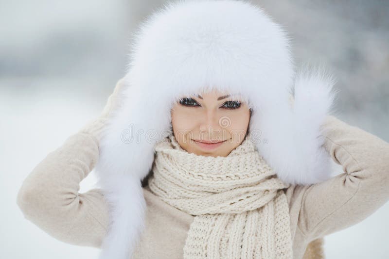 Winter portrait of beautiful smiling woman with snowflakes in white furs