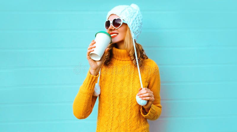 Winter portrait smiling young woman drinking coffee looking away wearing yellow knitted sweater, white hat with pom pom royalty free stock photography Winter portrait smiling young woman drinking coffee looking away wearing yellow knitted sweater, white hat with pom pom royalty free stock photography