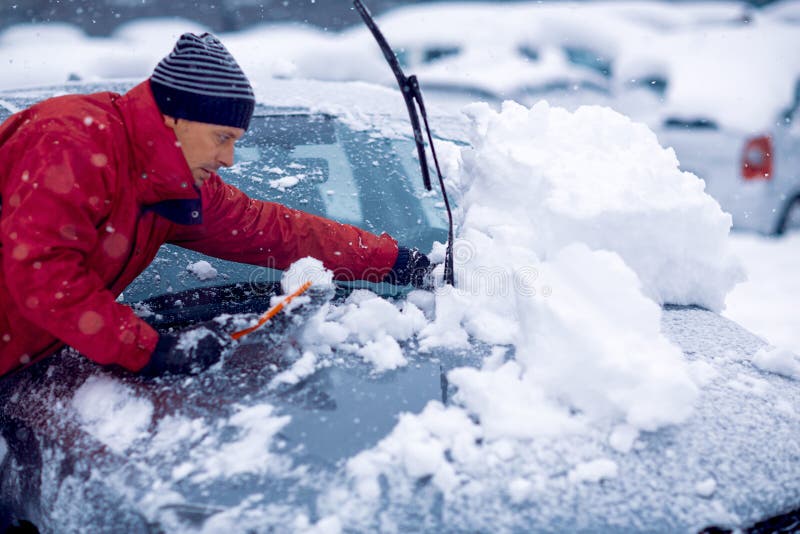 .Winter Problems of Car Drivers. Man Brushing the Snow Off His Car on a