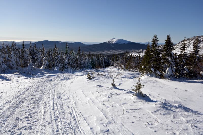 Winter road in forests and mountains. Taiga. Russia. royalty free stock photography