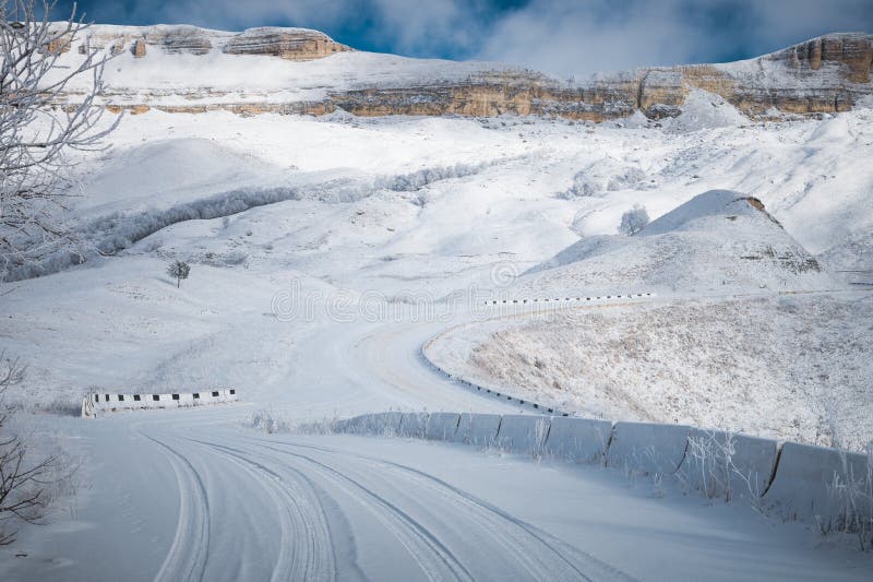 Winter road landscape of snow-covered cliffs of the plateau in the North Caucasus through the branches of a tree covered.