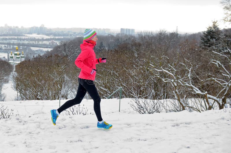 Winter running in park: happy active woman runner jogging in snow with Kyiv city skyline view, outdoor sport and fitness royalty free stock image Winter running in park: happy active woman runner jogging in snow with Kyiv city skyline view, outdoor sport and fitness royalty free stock image