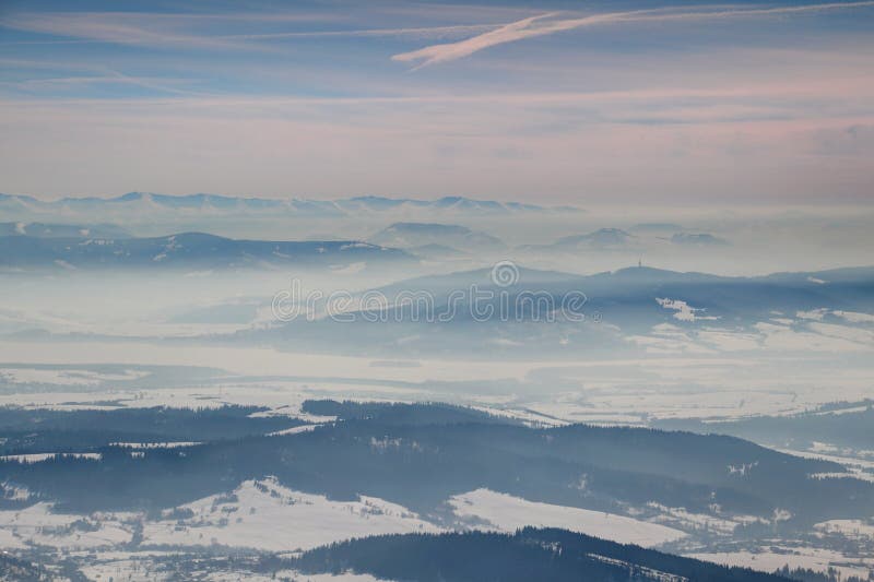 Zimní scenérie s mlhavě modrými hřebeny a údolími na Slovensku