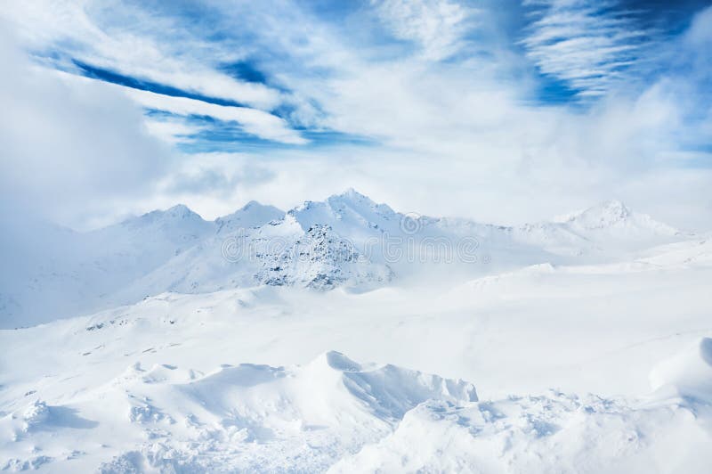 Winter snow-covered mountains and blue sky with white clouds