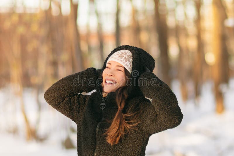 Winter snow fun happy girl walking outside in cold weather protecting ears holding wool hat over ears active outdoor