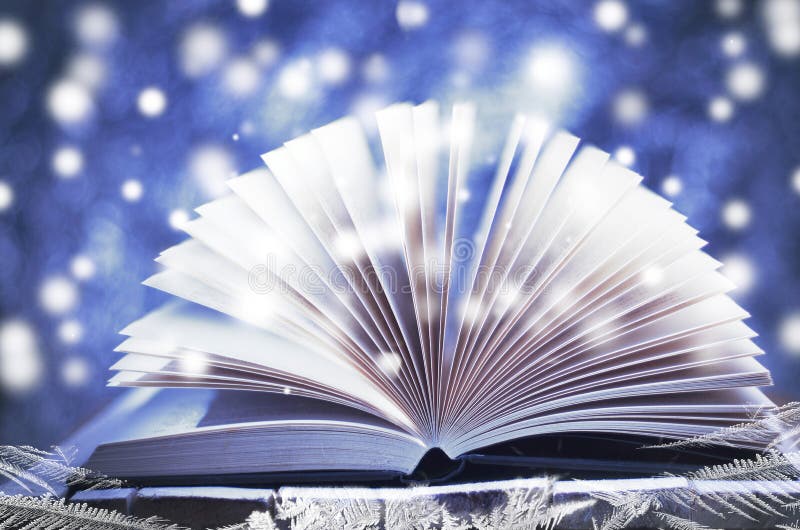 Winter story. Open book on wooden snowy blue background.