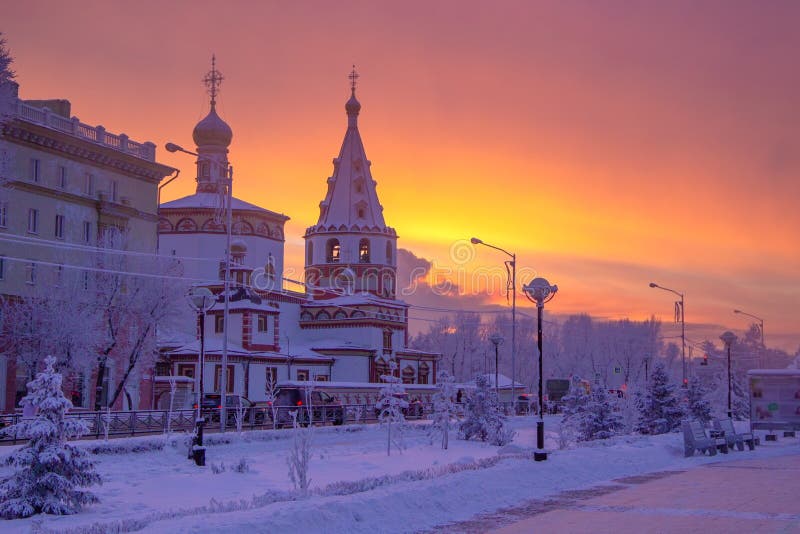 Winter sunset landscape of frosty trees, white snow in city park. Trees covered with snow in Siberia, Irkutsk near lake Baikal.