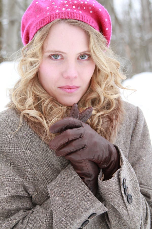 Portrait of a slightly smiling, wholesome, beautiful, green eyed young woman wearing a fur jacket, leather gloves and pink beret snow and trees. Portrait of a slightly smiling, wholesome, beautiful, green eyed young woman wearing a fur jacket, leather gloves and pink beret snow and trees.