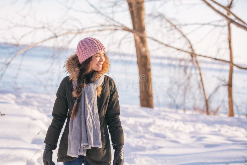 Winter woman walking out on forest walk in cold outdoor nature river outside. Happy asian girl model wearing wool hat