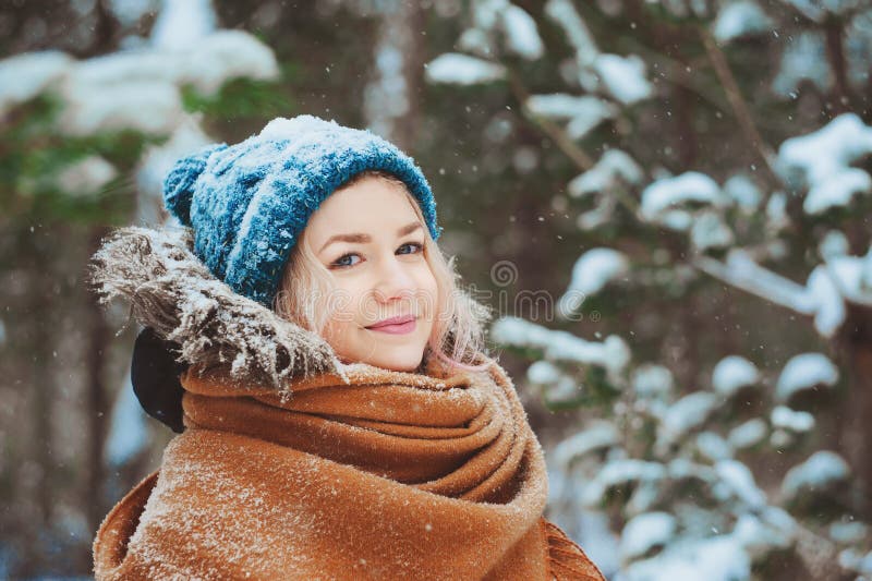 Winterporträt der glücklichen jungen Frau, die in schneebedeckten Wald in der warmen Ausstattung, in der Strickmütze und im Überf stockbild Winterporträt der glücklichen jungen Frau, die in schneebedeckten Wald in der warmen Ausstattung, in der Strickmütze und im Überf stockbild