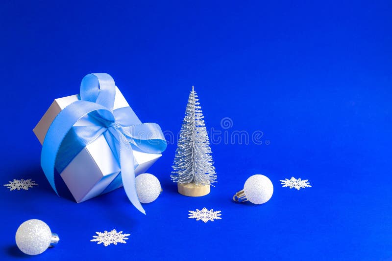 Winterschlussverkauf Weiße Geschenkbox mit dem blauen Band Winterbaum, Schneeflocken und Silber Bällen in der Weihnachtszusammens lizenzfreie stockbilder