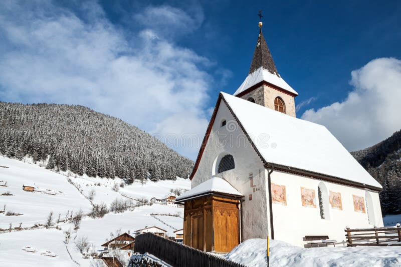 A wintertime view of a small church with a tall steeple