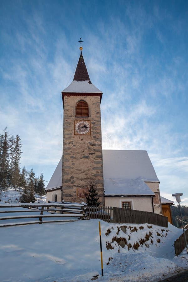 A wintertime view of a small church with a tall steeple