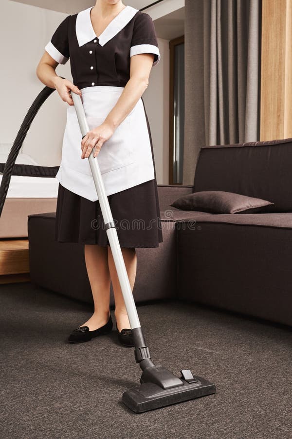 Wipe mess off. Horizontal cropped shot of maid in uniform cleaning living room of employer with vacuum cleaner, removing royalty free stock photography Wipe mess off. Horizontal cropped shot of maid in uniform cleaning living room of employer with vacuum cleaner, removing royalty free stock photography