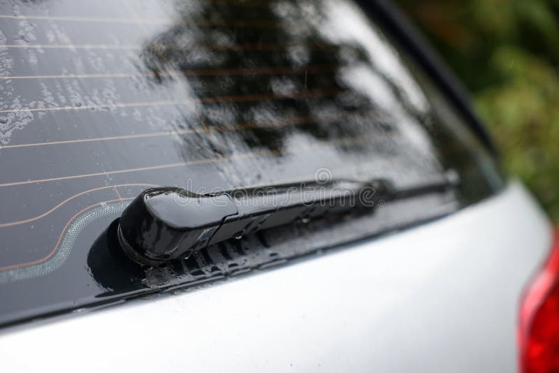 Wiper Cleaning Raindrops from Car Rear Windshield Outdoors Stock Photo