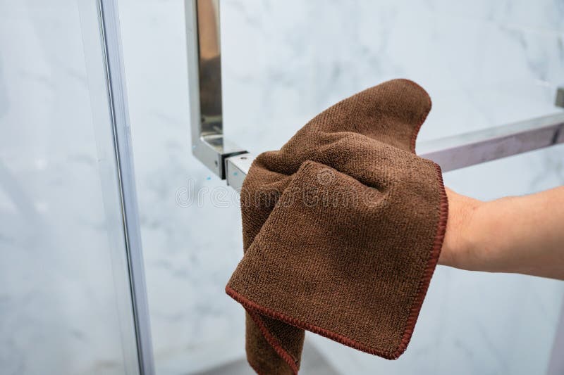 Wiping Door Handle with Microfiber Cloth in Bathroom Stock Photo