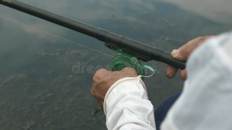 Wirbelnde Angelschnur des Fischers auf Spule auf See. Mann mithilfe von Angelruten- und geraderichtenangelschnur. Fang Fische des