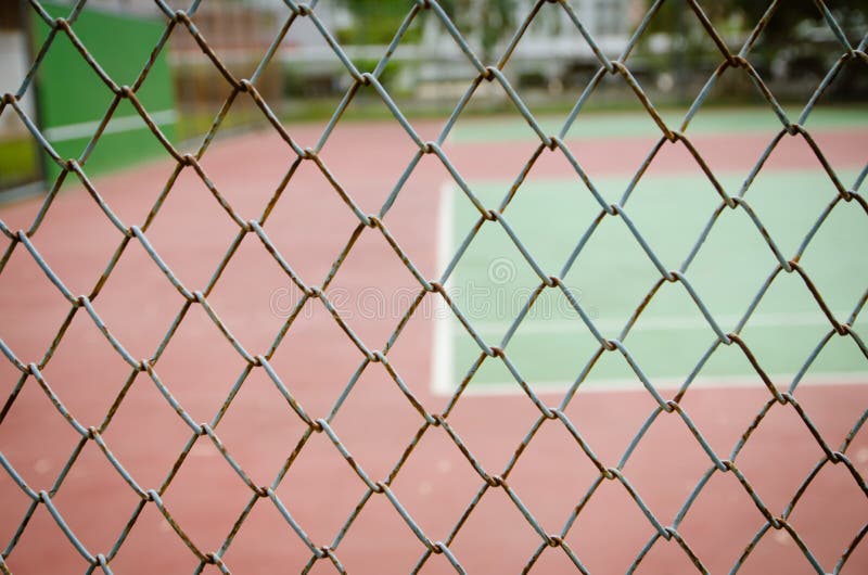 Wire fence with tennis court on background