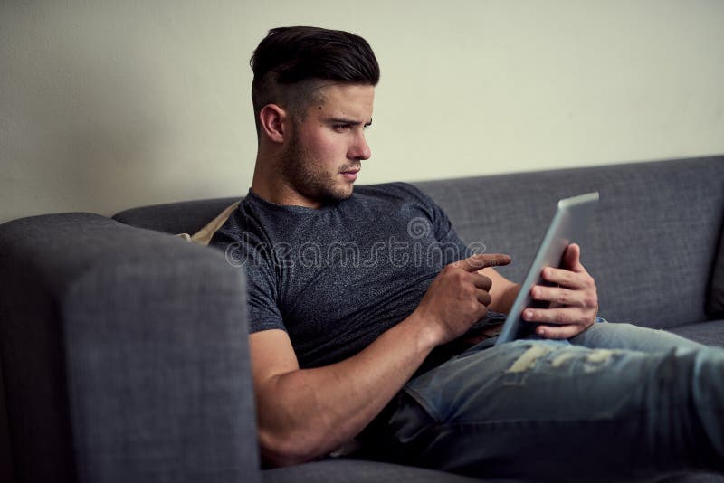 Wireless technology is the pinnacle of convenience. a focused young man using his tablet while sitting on the couch at royalty free stock photo