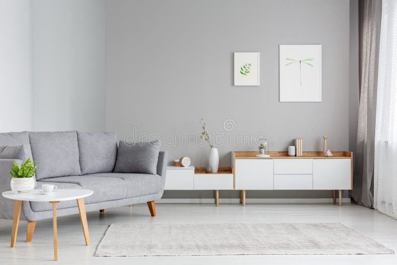 Wirkliches Foto eines geräumigen Wohnzimmerinnenraums mit grauem Sofa sta