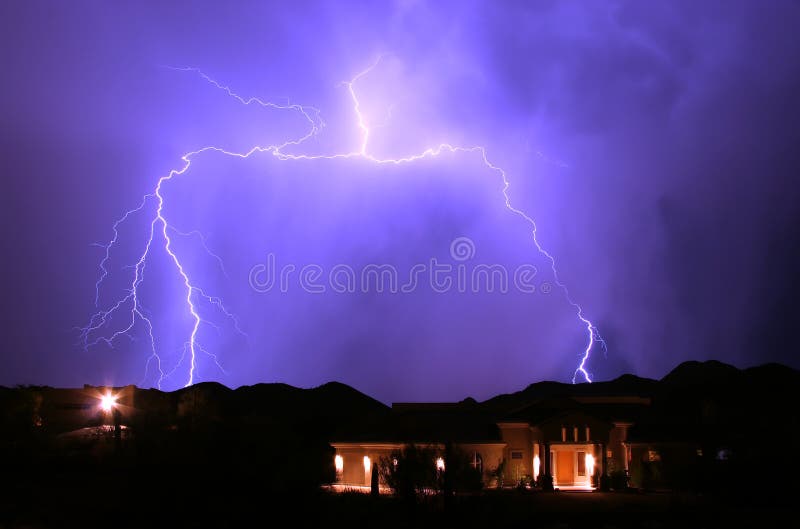 Lightning splits and strikes behind two homes in the hills outside of Phoenix, Arizona. Lightning splits and strikes behind two homes in the hills outside of Phoenix, Arizona.